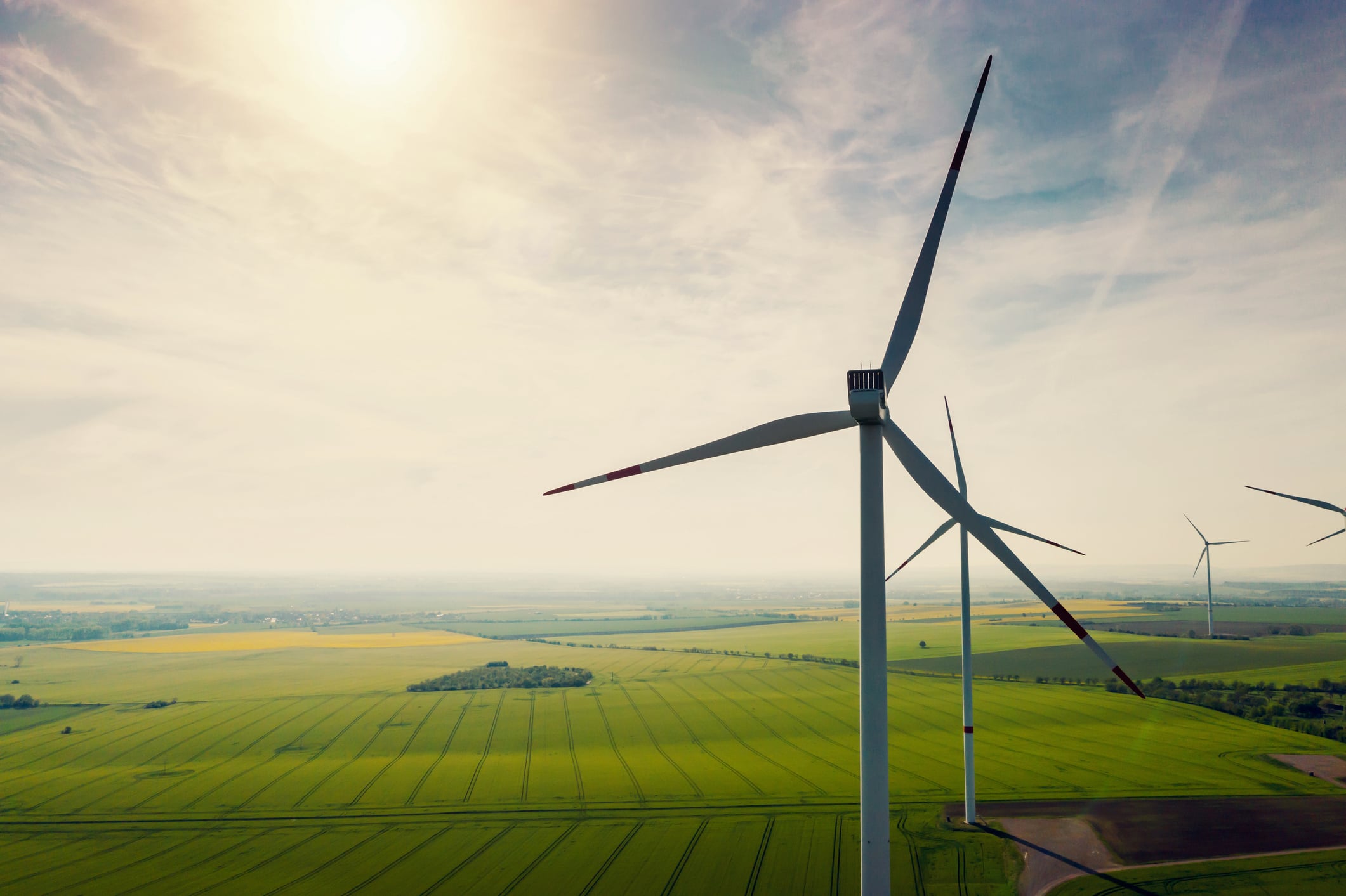 Windenergieanlagen über weiten grünen Feldern im Sonnenlicht