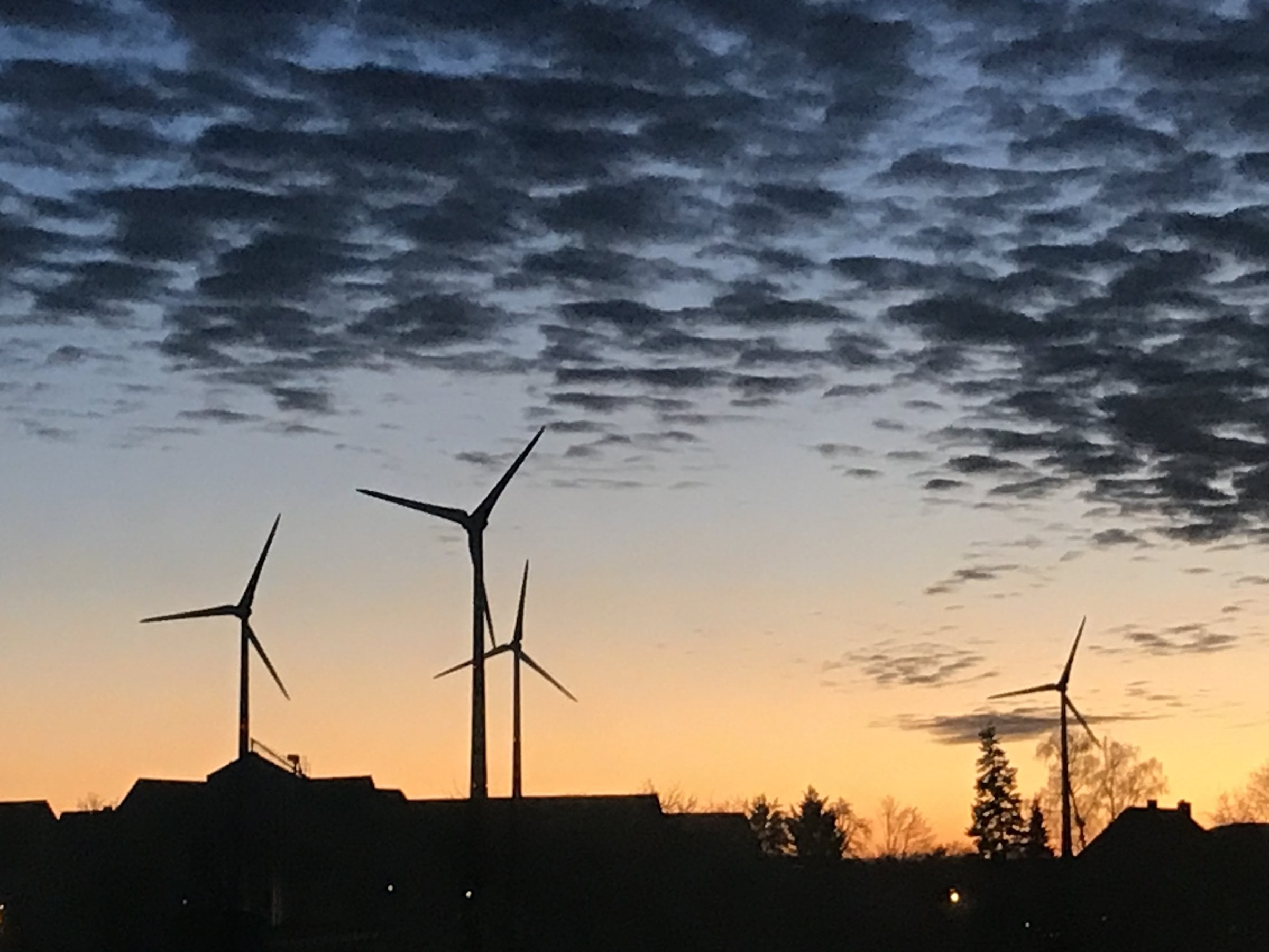 Windenergieanlagen in der Abenddämmerung unter einem wolkigen Himmel